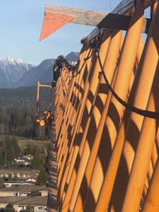 A man performing service maintenance at the top of a crane